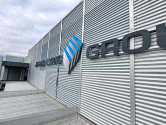 Front right and close view of signage lettering on a corrugated metal wall, overcast day